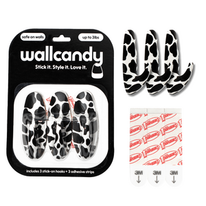 Wallcandy hook packaging with cow print hooks and adhesive strips on a white background