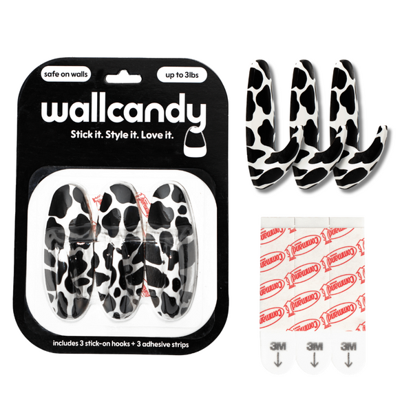 Wallcandy hook packaging with cow print hooks and adhesive strips on a white background