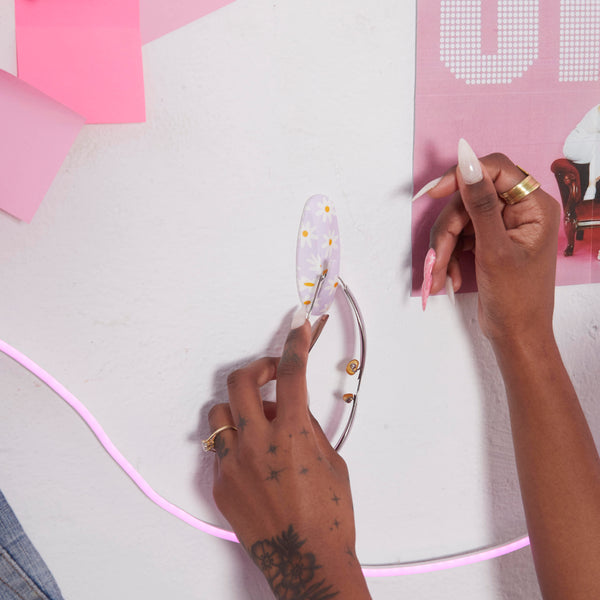 Person using a tool to remove a decorative letter from a wall with pink accents and 'SP' poster.