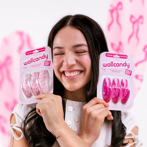 Woman holding two packages of wallcandy products against a pink background