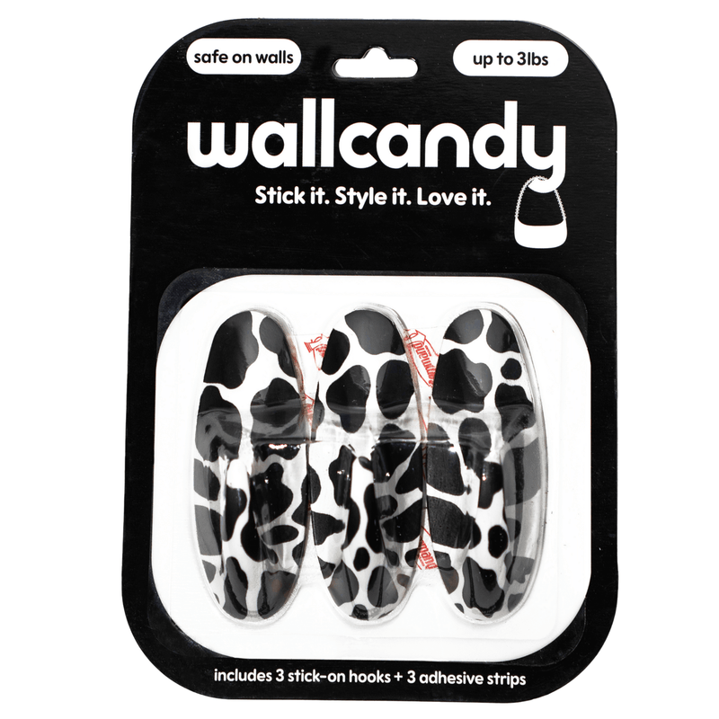 Packaging of Wallcandy wall hooks with cow print design on a white background